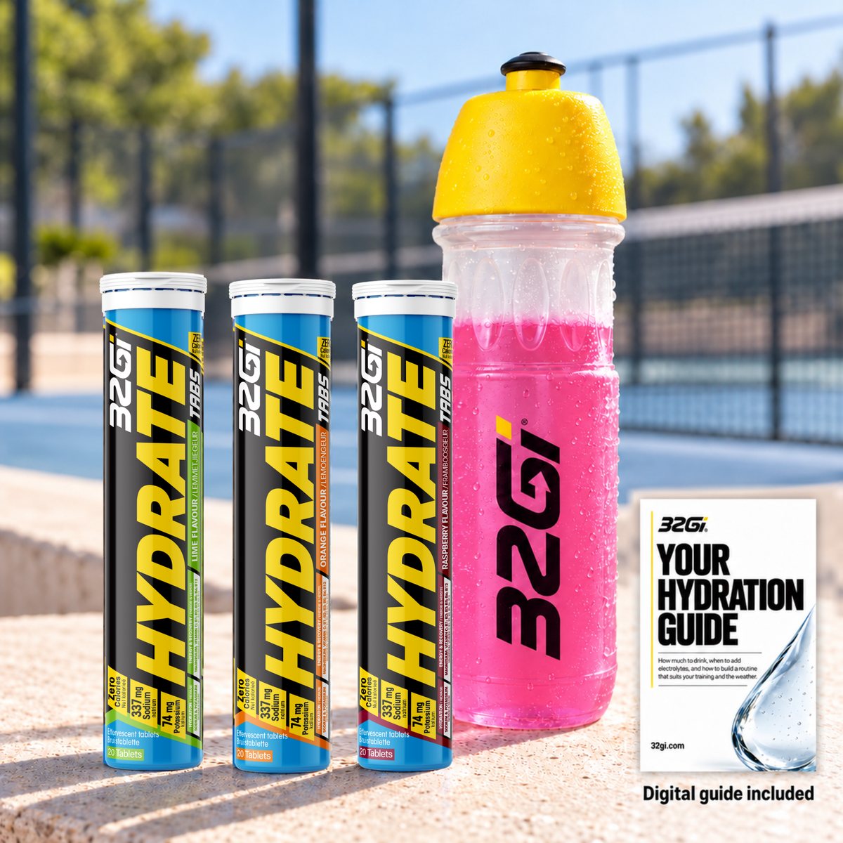 Your Hydrate bundle: three Hydrate tubes in Lime, Orange and Raspberry, the 32Gi bottle and Your Hydration Guide, at the edge of a padel court.